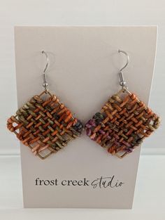 the earrings are made out of woven material and have small square shaped beads on them