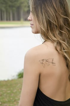 the back of a woman's shoulder with a small world map tattoo on it