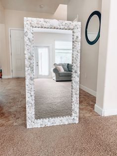 a large white mirror sitting on top of a carpeted floor next to a couch