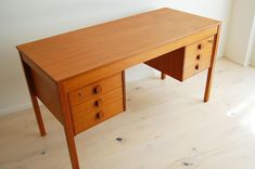 a wooden desk with three drawers on it in a room next to a white wall