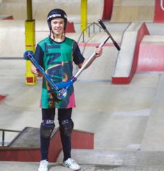 a young man standing on top of a skateboard ramp holding skis and poles