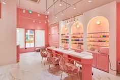 the interior of a nail salon with pink walls and marble counter tops, gold chairs and chandeliers