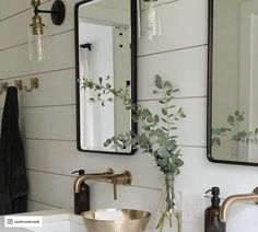 a bathroom sink with two mirrors above it and a vase filled with flowers on the counter