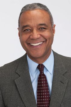 a man in a suit and tie smiling at the camera