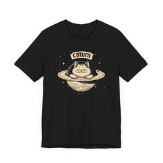 Caturn T-Shirt - Cosmic Cat Planet Graphic Tee 🌌🐱 Welcome to Caturn, the cutest planet in the galaxy! Our Caturn T-Shirt features an adorable cat lounging on Saturn’s rings, perfect for space enthusiasts and cat lovers alike. Made from high-quality fabric, this tee ensures both comfort and durability for your everyday adventures. Add a touch of cosmic cuteness to your wardrobe with this whimsical and unique graphic tee! 🌟✨ Why You'll Love It: 👕 Ultimate Comfort: Made with 100% Airlume combed Space Graphic Tee, Planet Graphic, Cat Lounging, Cosmic Cat, Cat Lounge, Cat Graphic Tee, Everyday Adventures, Cat Graphic, Outer Space