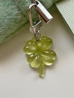 a green flower shaped keychain hanging from a silver chain on a white surface