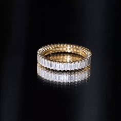 two gold and diamond rings on a black surface