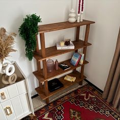 a wooden shelf with books and other items on it next to a rug in a room