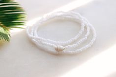 Matte Coconut white seed beads strung on stretch cord finished with a natural sea shell Bracelet can be wrapped around the wrist 3 times. Fits the average sized wrist (7 inches) The string total length is approximately 21 inches. Can also be worn as an anklet or a necklace. If you need a customized length or would like your bracelet to have more layers, please feel free to message me for a custom order! Handmade with love by Amanda 🐚 Surf wave bracelet can be found here: https://etsy.me/2DSXXfa Single Strand Beaded Bracelets With Round Beads For Beach, Beach Single Strand Beaded Bracelet With Round Beads, Beach Single Strand Beaded Bracelets, White Shell Beaded Bracelets For Summer, Summer White Shell Beaded Bracelets, White Strand Stretch Bracelet For The Beach, Adjustable Single Strand White Beads, Adjustable Single Strand White Bracelet, White Shell Beaded Strand Bracelets