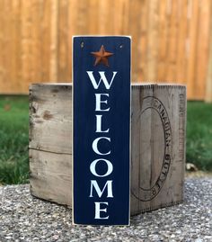 a wooden welcome sign sitting on top of gravel