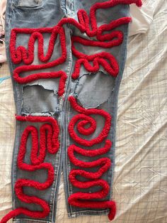 a pair of jeans that have been decorated with red yarn and the word love written on them