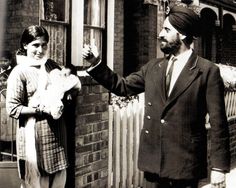 a man and woman standing next to each other in front of a brick building