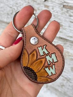 a hand holding a keychain with an embroidered flower on the front and back