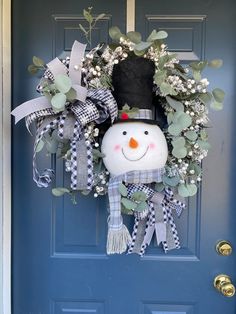 a snowman wreath on a blue door with greenery and a black top hat