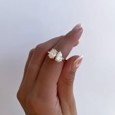 a woman's hand holding an engagement ring with two pear shaped diamonds