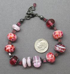 "In the mood for pink? Then this bracelet fits perfectly! It features a selection of my handmade pink lampwork beads. The colors range from dark translucent pink, pink and purple frit beads, to light pink swirls. These beads are simply stunning! Such a beautiful combination for Spring! The beads are strung along side sterling silver flower bead caps and pink Tourmaline rectangle shaped gemstone beads. I have made the lampwork beads in this bracelet. The sterling silver has been oxidized to add d Adjustable Pink Bracelets, Bohemian Pink Beaded Bracelets Czech Glass, Pink Bohemian Beaded Bracelets In Czech Glass, Bohemian Pink Beaded Bracelets From Czech Glass, Pink Czech Glass Bracelets With Colorful Beads, Pink Czech Glass Bracelets With Spacer Beads, Pink Czech Glass Bracelet, Pink Beaded Bracelets With Czech Glass, Pink Round Beaded Bracelets With Spacer Beads