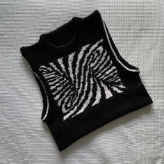 a black and white sweater with zebra print on the front is laying on a bed