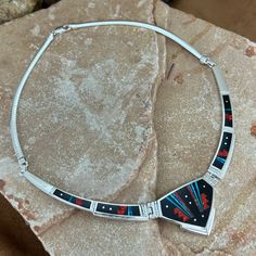 This gorgeous Sterling Silver Necklace, as part of the Red Moon collection, features Black Jade, Kingman Turquoise and Blue, Blue/Green & Red Lab Opal Dimensions: Center Link 1 3/4"W x 1 1/8"H; Total Length of Sterling Silver/Inlaid Links: 9"; Total Length of Necklace: 17" They are designed by David Rosales, one of the finest contemporary Southwest Artists in the world. He is the founder and co-owner of Supersmiths, Inc. of Gallup, NM. This Handcrafted Necklace is custom made and carries a lifet Artisan Red Jewelry With Large Pendant, Artisan Red Round Pendant Jewelry, Artisan Red Jewelry With Inlay, Red Sterling Silver Jewelry With Inlay, Artisan Red Inlay Jewelry, Red Multi-stone Necklaces As Gifts, Red Multi-stone Necklace For Gift, Blue Necklace With Round Inlay, Collectible Blue Inlay Necklace