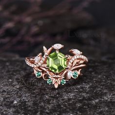 a ring with green stones and leaves on the outside, sitting on a rock in front of a dark background