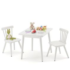 a white table with two chairs and a teddy bear