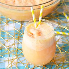 two glasses filled with orange juice on top of a blue and white table cloth next to a bowl full of oatmeal