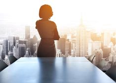 a woman standing at a conference table in front of a cityscape with skyscrapers