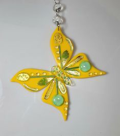 a yellow and green flower shaped necklace on a white surface with a chain attached to it