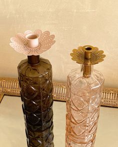 two glass vases sitting on top of a table next to each other, one with a candle in it