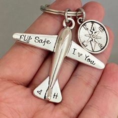 a hand holding a silver airplane key chain