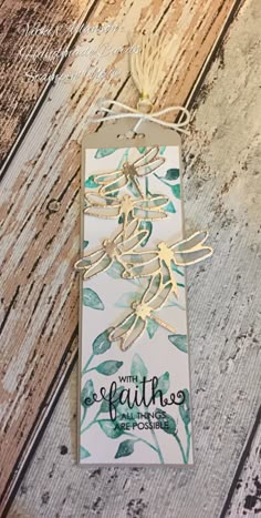 a card with some leaves on it and the words faith written in gold foil is hanging from