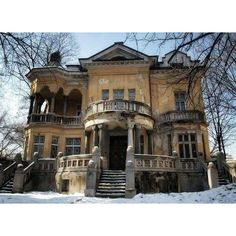 an old house with snow on the ground and stairs leading up to it's second story