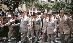 a group of men walking down a street next to each other in front of a crowd