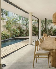 the dining room table is surrounded by wooden chairs and an outdoor area with large windows