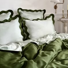 a bed with green sheets and white pillows