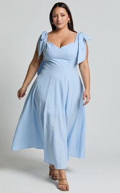 a woman in a blue dress posing for the camera with her hands on her hips