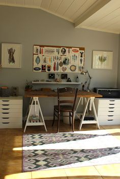 a room with two desks and several pictures on the wall above them, along with a rug