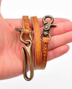 a person holding two different types of bracelets in their hand and one has a hook on it