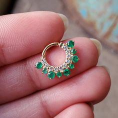 This stunning natural diamond and natural green emerald clicker style earring is a perfect accessory for your septum and daith. Crafted in 14k solid gold and a secure click mechanism, this ring fits like a charm. * Gold - 14k, Solid gold * Inner Diameter : 6 mm, 7 mm, 8 mm, 9 mm * Gauge : 18g, 16g, 14g * Gemstone 1 : Natural White diamond * Color/Clarity : H-I, Vs-Si * Gemstone 2 : Natural Emerald (for other gemstones, please convo) * Type : Clicker Find us on Instagram for exquisite designs: @a Halo Emerald Jewelry With Round Cut, Emerald Halo Jewelry With Round Cut, May Birthstone Hoop Gemstone Jewelry, Green Halo Jewelry With Round Cut, Green Gemstone Accents Jewelry With Round Cut, 14k Gold Halo Jewelry For May Birthstone, 14k Gold Jewelry With Green Prong Setting, May Birthstone Gemstone Huggie Jewelry, 14k Gold Jewelry With Green Gemstone Accents