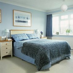 a bedroom with blue walls and carpeted flooring has a large bed in it