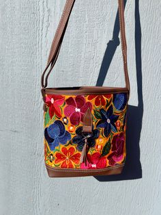 *Please advise each bag has a different design and color background. It might not be the exact flowers/ color background as the image. If you want a specific design please message us for photos* The vibrant embroidered flowers that are carefully crafted by artisans in Mexico bring beauty to this bag. You can style this as a shoulder or crossbody bag for any occasion.Measurements: 10 inches (width) x 8 1/2 (length)Made with Synthetic Faux Leather-Adjustable straps-Zipper closure pocket-Back Zippe Multicolor Embroidered Shoulder Satchel, Multicolor Embroidered Satchel Shoulder Bag, Embroidered Multicolor Satchel Tote, Casual Brown Embroidered Shoulder Bag, Embroidered Tote Bucket Bag For Everyday Use, Spring Multicolor Floral Embroidered Shoulder Bag, Multicolor Floral Embroidered Tote Shoulder Bag, Multicolor Floral Embroidered Tote Bag, Multicolor Floral Embroidered Shoulder Bag