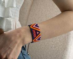 a woman is wearing a colorful bracelet on her arm and holding onto a white shirt