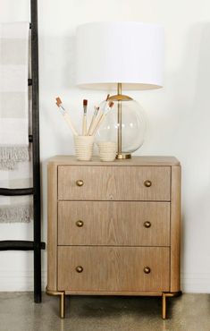 a wooden dresser sitting next to a white lamp