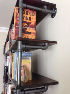 a book shelf with books on it and pipes running down the wall behind it,