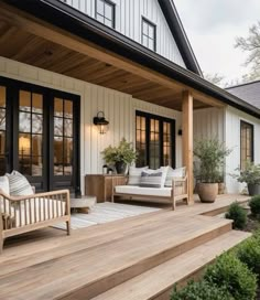 a porch with wooden steps leading up to the front door and patio furniture on it