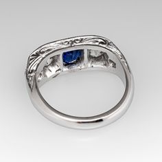 This lovely circa 1930s antique sapphire ring is centered with one (1), bead set, oval cut natural blue sapphire weighing 0.81 carats and flanked to each side by one (1), bead set, old European cut diamond. The shoulders of the ring are each bead set with two (2) round single cut diamonds. The gemstones are bordered with milgrain edging. Engraved details accent the side faces of the ring. The ring measures 7.3mm at the top, rises 3.7mm above the finger, tapering to 2.9mm wide and 1.6mm thick at the base of the shank. The ring is currently a size 6 and we offer complimentary resizing to fit. Classic Oval Cabochon Sapphire Ring With Bezel Setting, Classic Sapphire Ring With Oval Cabochon Bezel Setting, Classic Sapphire Ring In 14k White Gold, Classic Sapphire Birthstone Ring, Classic Oval Sapphire Ring, Classic Sapphire Halo Ring, Classic Oval Sapphire Ring With Polished Finish, Elegant Sapphire Signet Ring, Classic Sapphire Ring Oval Cabochon