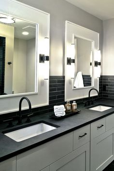 a bathroom with two sinks, mirrors and lights on the side of the sink area