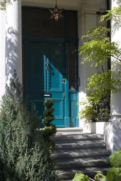 a blue door is on the side of a white building with steps leading up to it