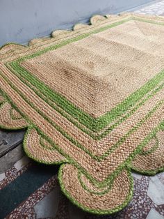 a green and beige rug sitting on top of a wooden floor