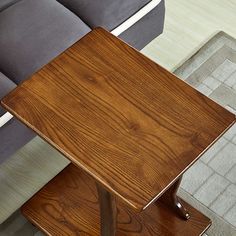 a wooden table sitting on top of a carpeted floor next to a gray couch