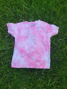 a pink and blue tie dye shirt laying on the grass